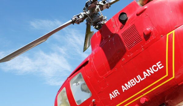 Red helicopter of air ambulance isolated on blue sky background. Detail of the helicopter blades. Cornwall, UK Red helicopter of air ambulance isolated on blue sky background. Detail of the helicopter blades. Cornwall, UK